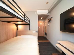 a hotel room with a bed and a flat screen tv at Super Hotel Hiroshima in Hiroshima