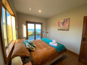 a bedroom with a bed with a view of the ocean at Wild Weka Eco Stay - Off-Grid 4WD RECOMMENDED in Waimarie