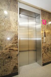 an elevator in a building with a stone wall at BoA Travel House in Seoul