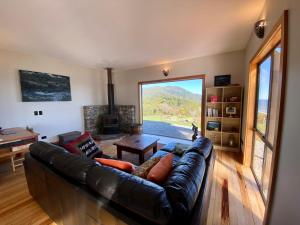 a living room with a leather couch and a fireplace at Wild Weka Eco Stay - Off-Grid 4WD RECOMMENDED in Waimarie