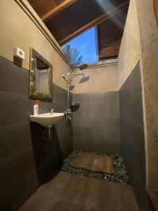 baño con lavabo y ducha con ventana en Kubu Bakas Guest House - CHSE Certified en Banjarangkan