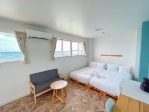 a bedroom with a bed and a chair and a window at マイビーチリゾート in Kin