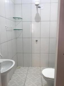 een witte badkamer met een toilet en een wastafel bij Quarto Dani in Jericoacoara