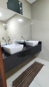 Baño con 2 lavabos en una encimera negra en Duplex com piscina no Grangeiro, en Crato