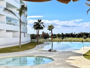 una piscina frente a un edificio con palmeras en Chic Beachside Getaway, en Motril