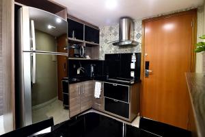 cocina con armarios negros y nevera de acero inoxidable en Tropical Executive 1006, en Manaus