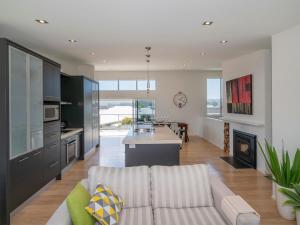 a living room with a couch and a kitchen at Aquila Waters - Whitianga Holiday Home in Whitianga