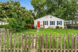 a white house with a red door behind a fence at 2 Bed Townhouse: Minutes from DCA-National Airport in Alexandria