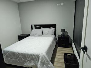 a bedroom with a bed with white sheets and two night stands at apartamento de lujo in Cuenca
