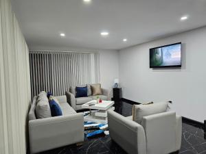 a living room with couches and a tv on the wall at apartamento de lujo in Cuenca