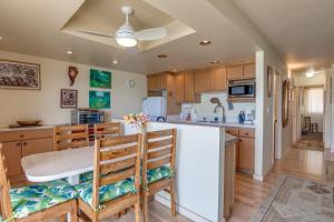 a kitchen with wooden cabinets and a table and chairs at Maui Sands #5G in Kahana