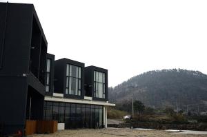 ein schwarzes Gebäude mit einem Berg im Hintergrund in der Unterkunft Jeju Claire de lune in Jeju-do