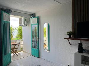 Zimmer mit grüner Tür und Balkon in der Unterkunft Studio de l'Anse Mitan in Les Trois-Îlets