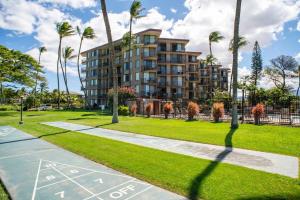 een gebouw in een park met palmbomen en een stoep bij Refined Oceanfront Retreat in Kihei