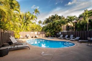 a swimming pool with chairs and a fence at Tropical & Serene Ground Floor in Kihei