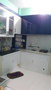 uma cozinha com armários brancos e paredes azuis em Homestay Sake em Lai Sơn