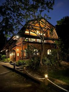 una gran casa de madera con luces encendidas por la noche en The Country House en Senggigi 