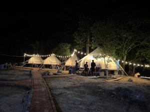 eine Gruppe von Menschen, die nachts vor Zelten stehen in der Unterkunft Homestay Sake in Lai Sơn
