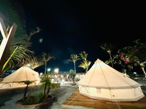 zwei weiße Zelte, die nachts neben einer Straße sitzen in der Unterkunft Suly's Village Phan Thiết in Phan Thiet