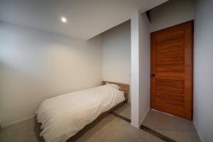 a small bedroom with a bed and a wooden door at THE SECOND Kujukuri Beach House in Kujukuri