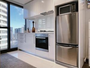 Una cocina con electrodomésticos de acero inoxidable y una gran ventana. en Prima Tower 1B Apt by GoodLive, en Melbourne