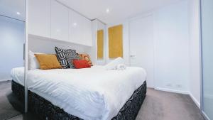 Un dormitorio con una gran cama blanca con almohadas de colores. en Prima Tower 1B Apt by GoodLive, en Melbourne 27 fotos más
