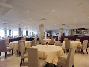 巴淡島中心的住宿－Grand Sydney Hotel，一间设有白色桌椅的用餐室