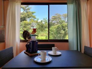une table avec deux tasses de café sur une table et une fenêtre dans l'établissement Casita Los Guarumos (Finca Las Colinas), à Bijagua