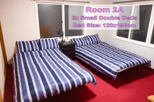 twee bedden in een kamer met blauwe en witte strepen bij Furano House, JR Station, 2F Apartment, 3 Bedrooms, Max 8PP - 6 Adults 2 Kid, Onsite Parking in Furano