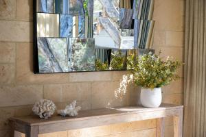 a mirror and a vase on a table with flowers at Paperbarks I Private Properties in Dunsborough +16 photos