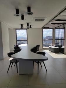 uma mesa branca e cadeiras num quarto com janelas em Studio Perdizes em São Paulo