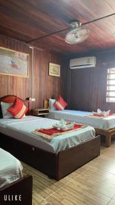 two beds in a room with wooden walls at Villa Thavisouk Legend - Luang Prabang in Luang Prabang