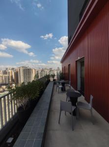 uma varanda com mesas e cadeiras num edifício vermelho em Studio Perdizes em São Paulo