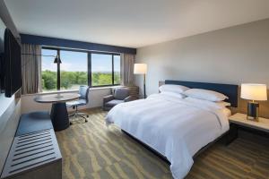 a hotel room with a large bed and a desk and chair at Portland Sheraton at Sable Oaks in South Portland