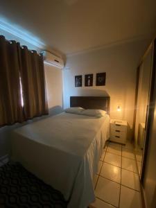 a bedroom with a white bed and a night stand at Apto refúgio 101 em São Luís/MA (inteiro) in São Luís