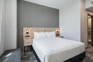 a bedroom with a large white bed and a nightstand at Sandman Signature Fort Worth Downtown Hotel in Fort Worth