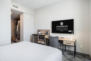 a bedroom with a bed and a desk with a tv at Sandman Signature Fort Worth Downtown Hotel in Fort Worth