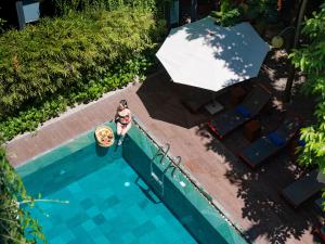 a woman standing next to a swimming pool with an umbrella at Mulberry Collection Silk Eco in Hoi An