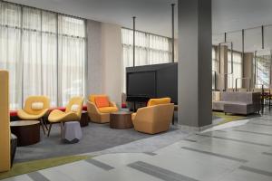 a lobby with yellow and orange chairs and a flat screen tv at SpringHill Suites by Marriott New York Queens in Queens