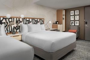 a hotel room with two beds and a chair at SpringHill Suites by Marriott New York Queens in Queens