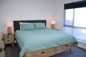 una camera da letto con un letto con un piumone verde e una finestra di The Baltimore House - Family Getaway a Port Lincoln