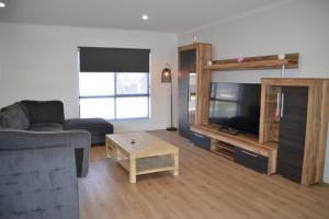 a living room with a couch and a flat screen tv at The Baltimore House - Family Getaway in Port Lincoln