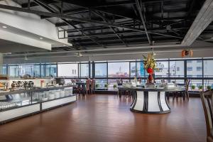 a restaurant with tables and chairs in a room with windows at Ohana Phnom Penh Palace Hotel in Phnom Penh