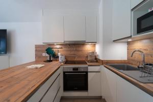Una cocina con gabinetes blancos y una encimera de madera. en Au bonheur du lac charmant appartement pour 4 personnes, en Duingt