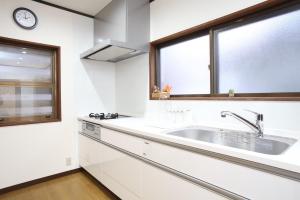 a white kitchen with a sink and two windows at Bond Chalet Hakuba - Vacation STAY 76698v in Hakuba