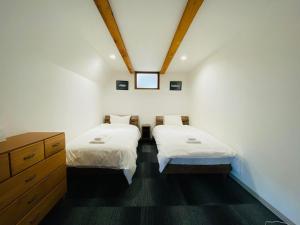a bedroom with two beds and a dresser in it at Bond Chalet Hakuba - Vacation STAY 76698v in Hakuba