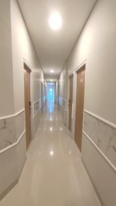 un corridoio vuoto in un edificio con pavimenti e soffitti bianchi di Ghurfati Hotel Wedana a Giacarta