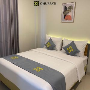 a bedroom with two beds with yellow and gray pillows at Ghurfati Hotel Wedana in Jakarta
