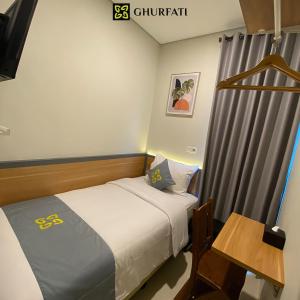 een kleine slaapkamer met een bed en een tafel bij Ghurfati Hotel Wedana in Jakarta