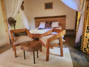 a bedroom with a bed with a desk and a chair at Haradali's Home in Arusha
